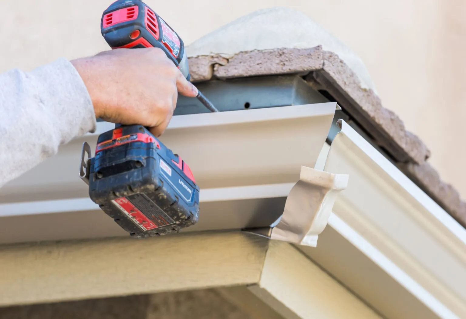 Close-up of a cordless drill used for a repair at the edge of a home roof